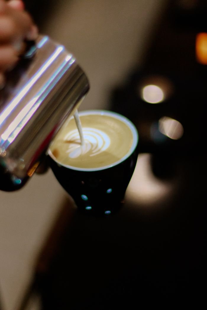 Elegant latte art being poured into a ceramic coffee cup, showcasing barista skills.